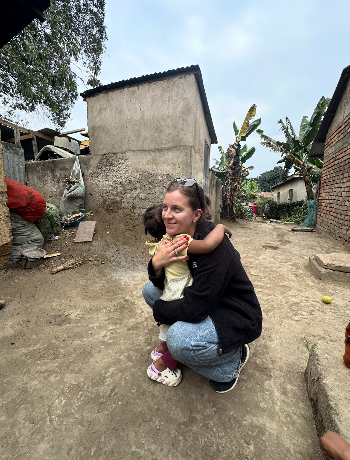 Two people standing close together outdoors in Arusha, arms around one another.