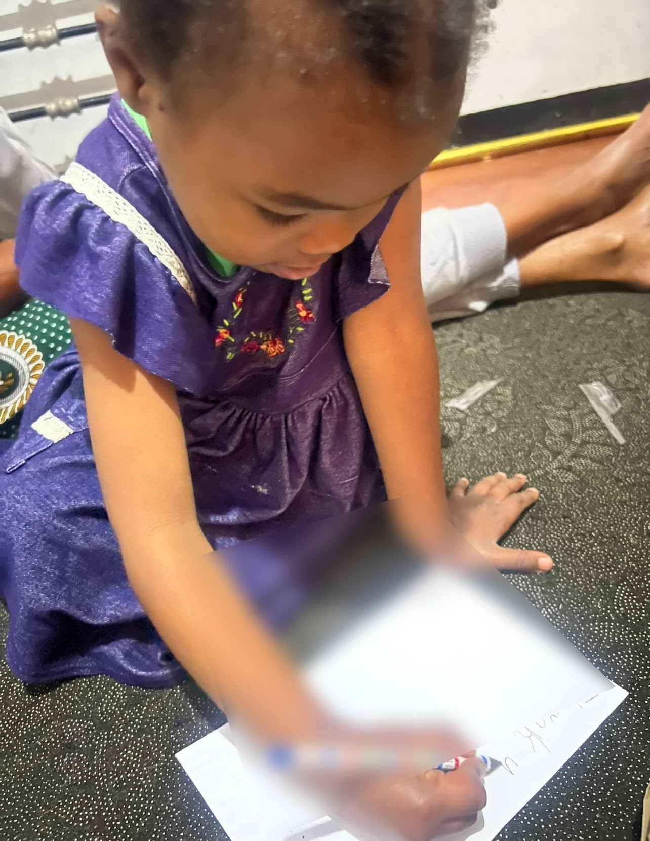 Nurath drawing a letter for a sponsor; the writing is obscured for privacy.