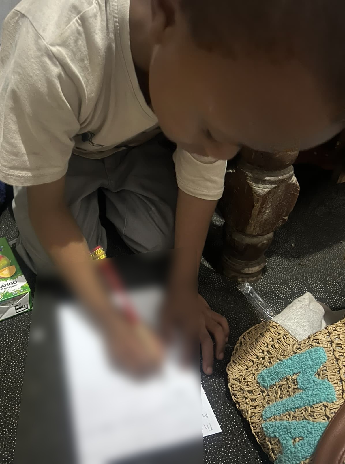 A child writing a letter for a sponsor; the writing is obscured for privacy.